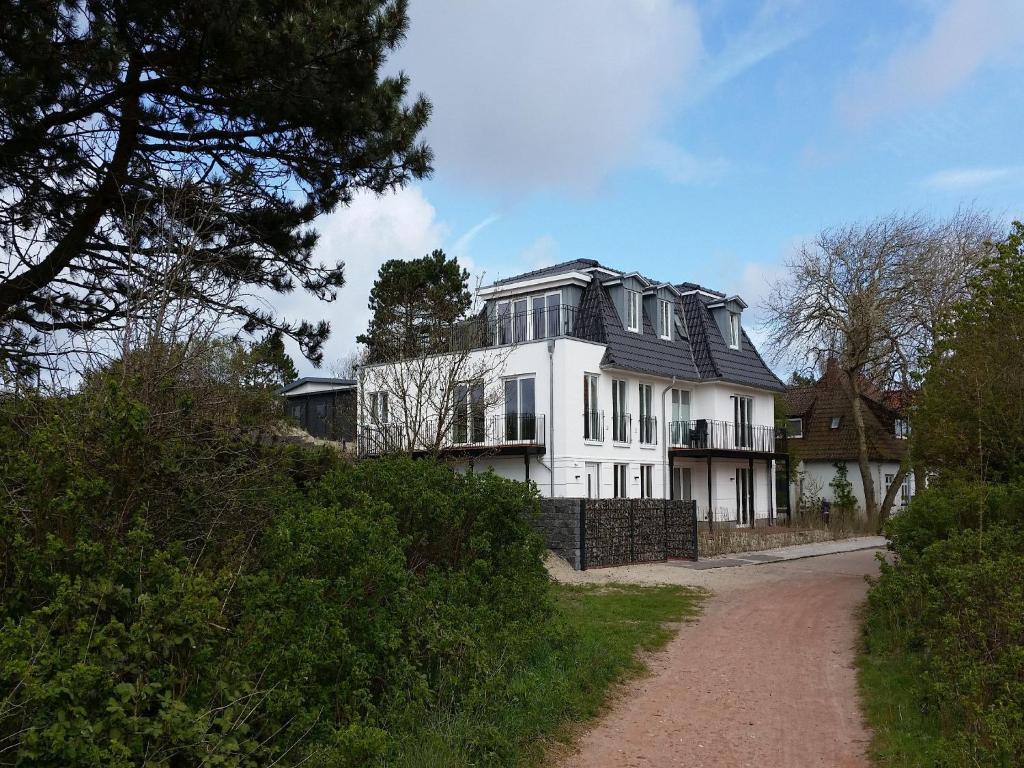 ein weißes Haus mit schwarzem Dach auf einem Hügel in der Unterkunft Blanker Hans Wohnung 4 in Wangerooge