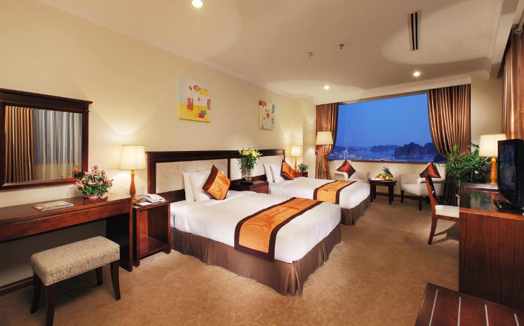 a hotel room with two beds and a large window at Ha Long DC Hotel in Ha Long