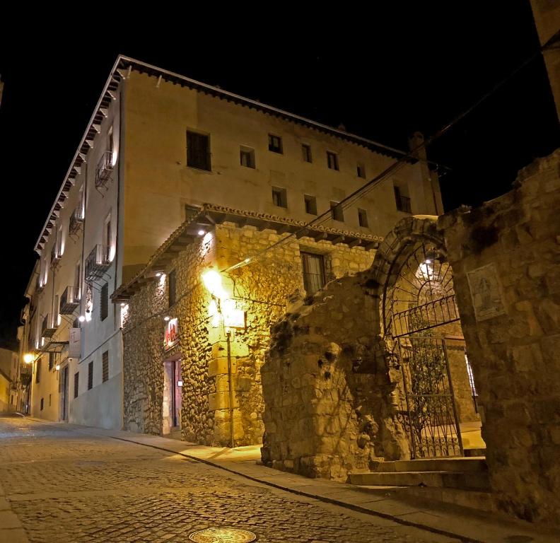 an old stone building with lights on a street at night at Hotel Convento Del Giraldo in Cuenca