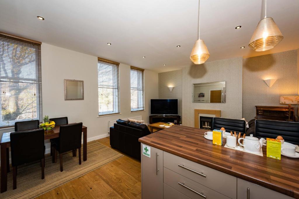 
a kitchen with a table, chairs and a refrigerator at Abbey Apartments in Barrow in Furness
