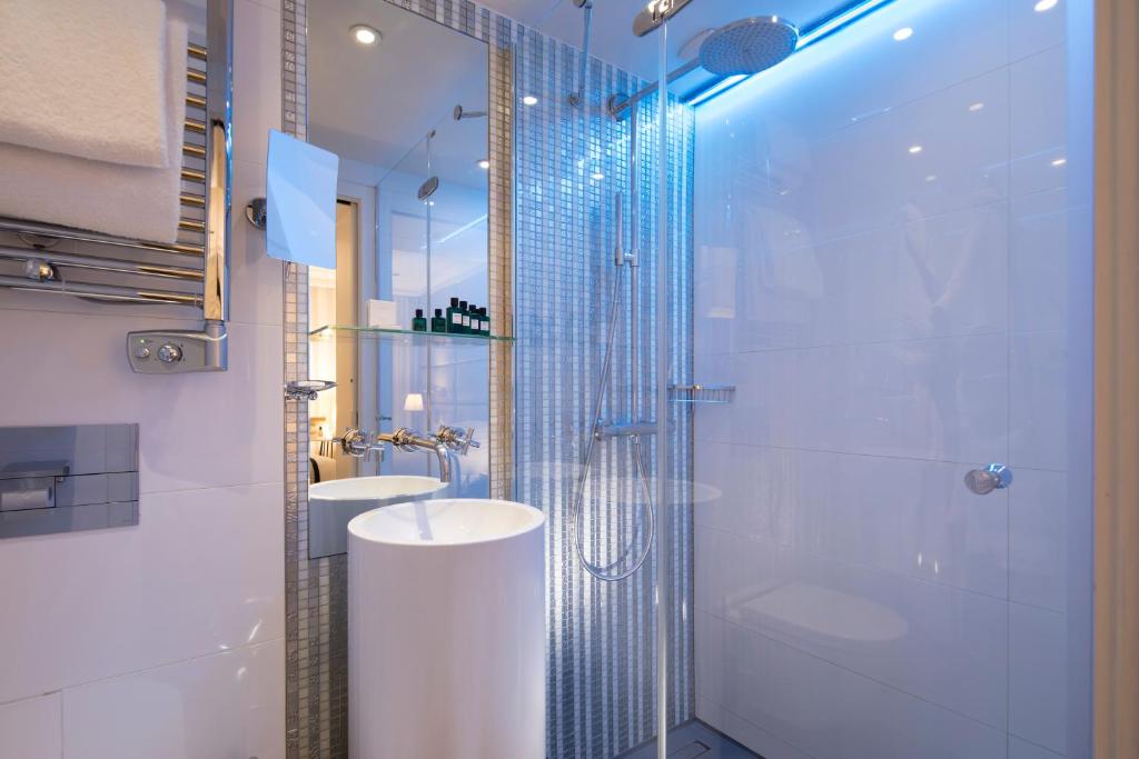 y baño con ducha, aseo y lavamanos. en Hôtel R de Paris - Boutique Hotel, en París