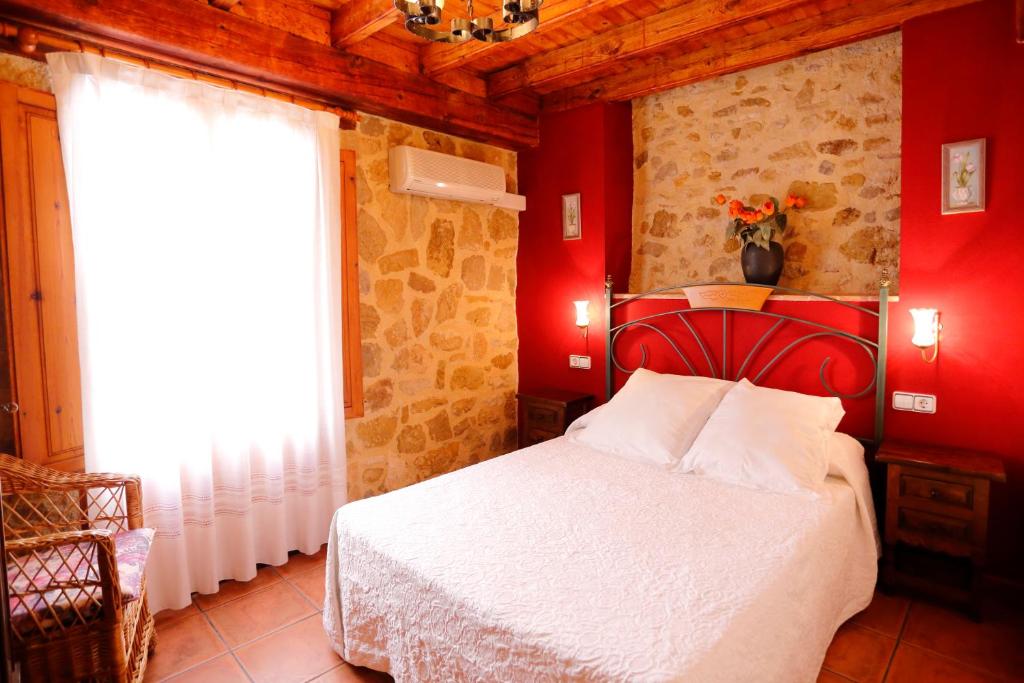 1 dormitorio con 1 cama con pared roja en El Refugi del Maestrat A - Turistrat, en Cervera del Maestre