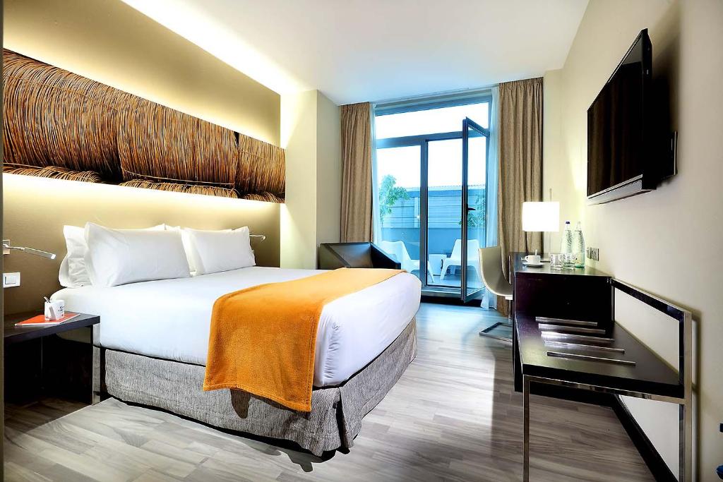 プエルト・デ・サグントにあるExe Puerto de Saguntoのベッドとバルコニー付きのホテルルーム