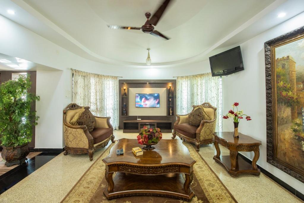 a living room with chairs and a table and a tv at Shoolin Resorts in Manipal