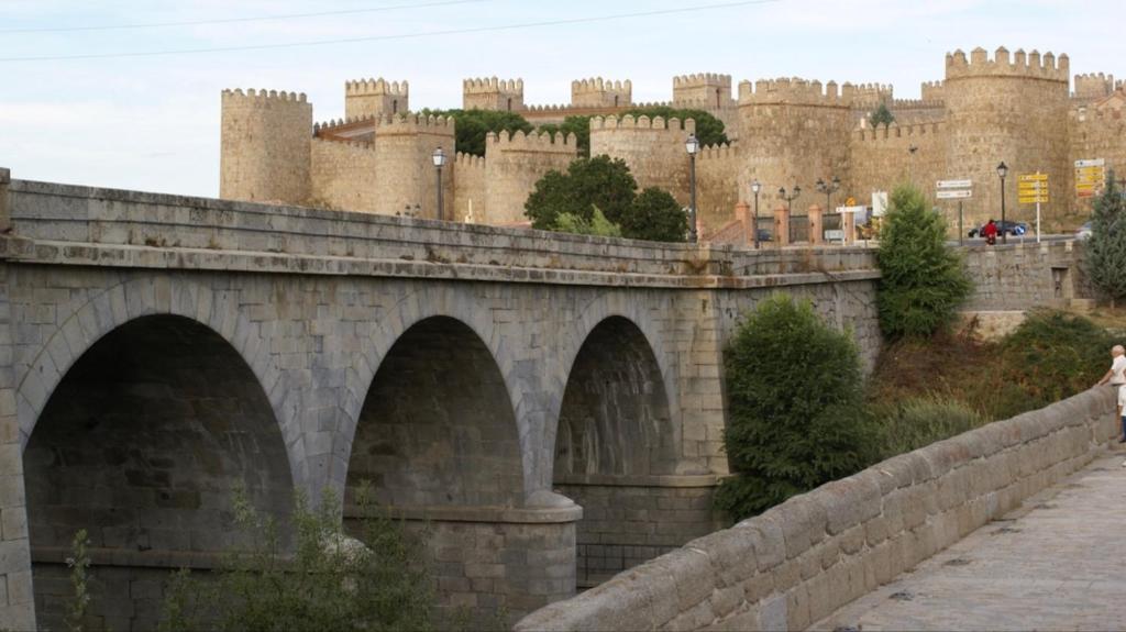 uma ponte de pedra com um castelo ao fundo em Casa Serapio em Ávila