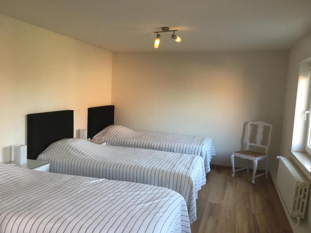 a hotel room with two beds and a chair at De Lanterfanters Vakantiehuis Jef in Nieuwpoort