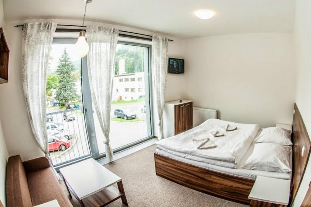 1 dormitorio con cama y ventana grande en Luxusní horský apartmán přímo u sjezdovky Kouty en Loučná nad Desnou