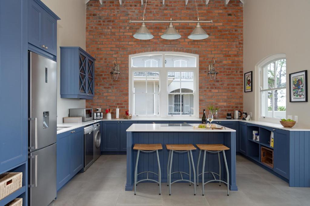 a kitchen with blue cabinets and a brick wall at Le Vine Constantia in Cape Town