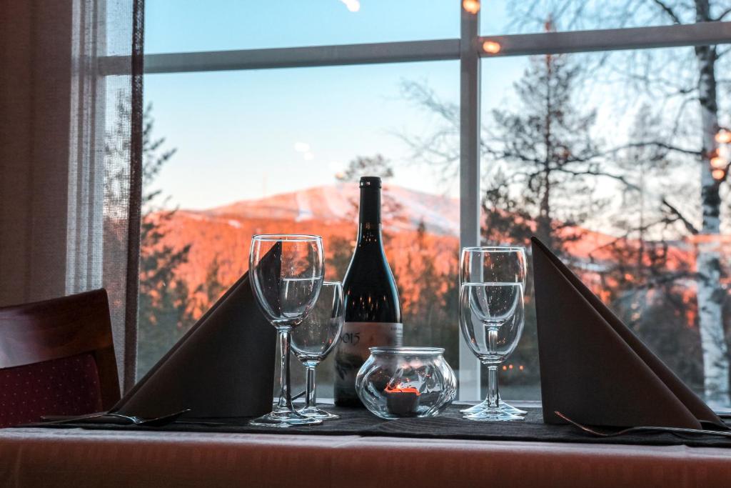 una mesa con dos copas y una botella de vino en Hotel Ylläsrinne en Ylläsjärvi