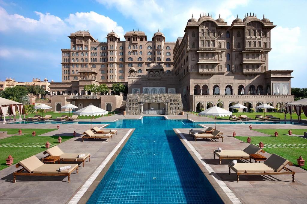 a hotel with a swimming pool in front of a large building at Fairmont Jaipur in Jaipur