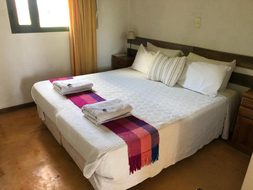 a bedroom with a large bed with two towels on it at Tikaykilla Lodge & Wines in Maipú