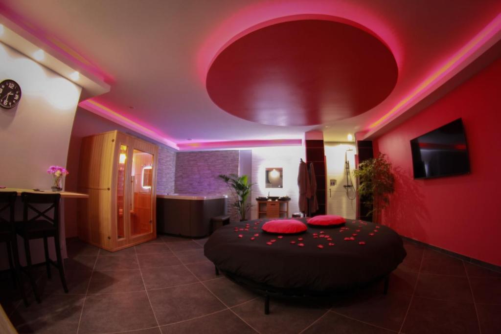 Le RoveにあるNuit vip spa sauna privatifのピンクの照明が付いたベッドが備わる客室です。