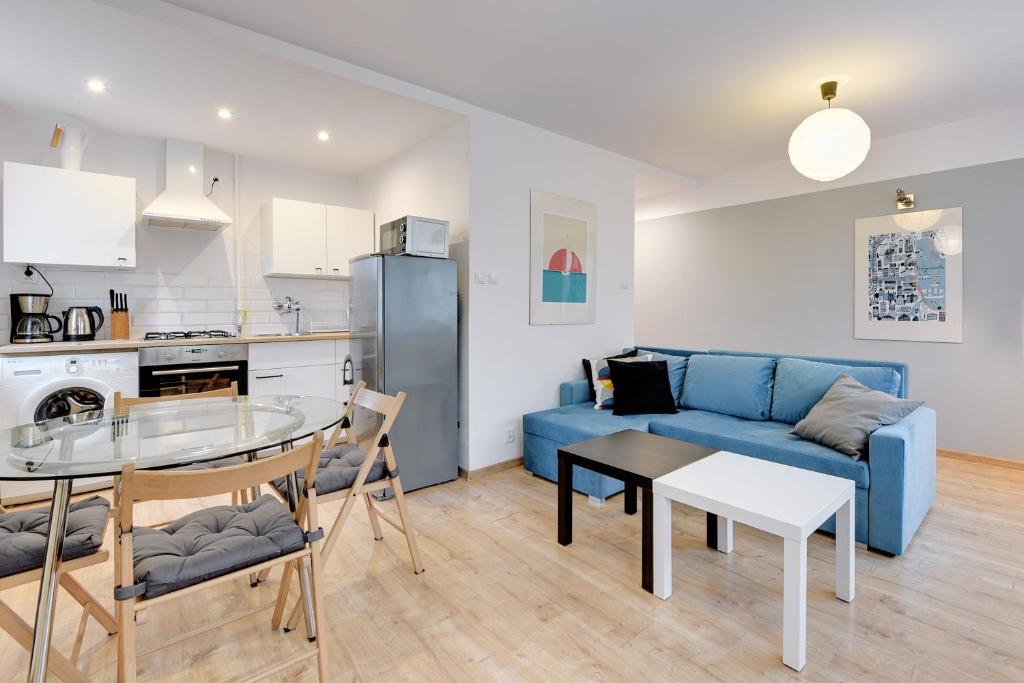 een woonkamer met een blauwe bank en een tafel bij Gdańsk Comfort Apartments Wejhera in Gdańsk