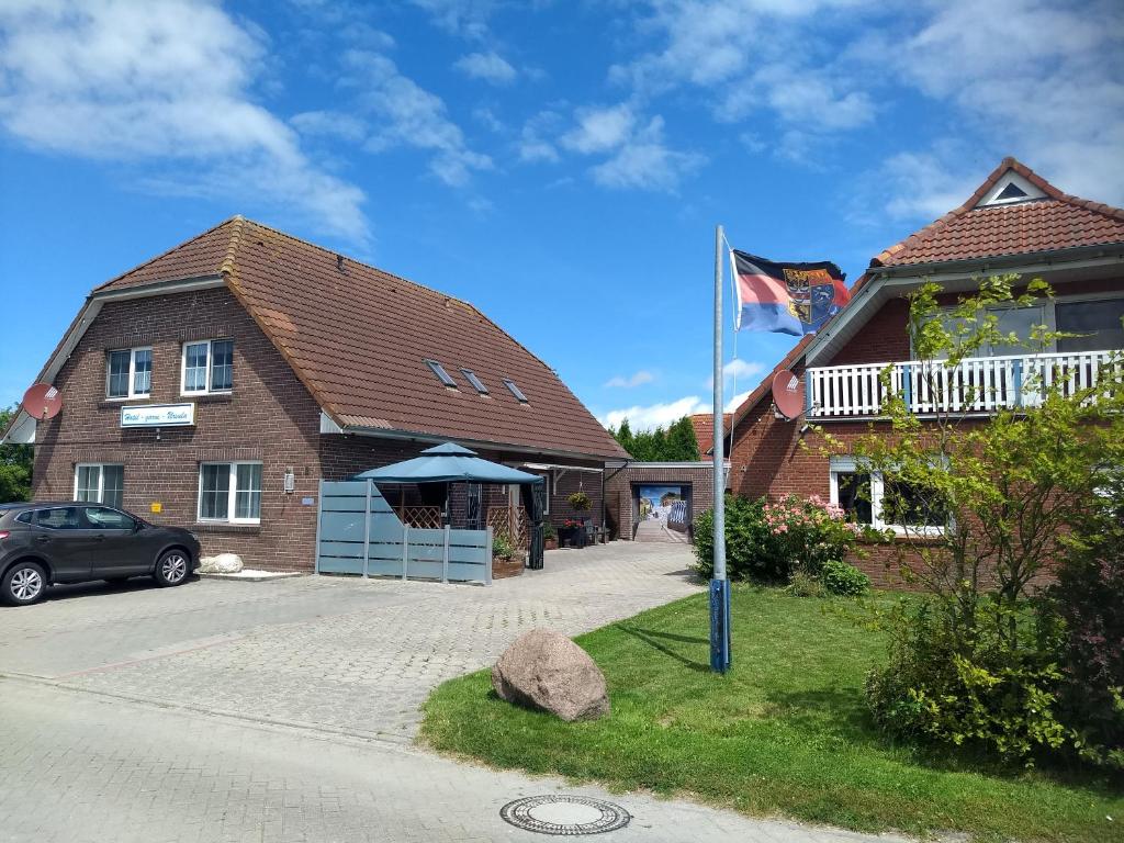 una casa con una bandera delante de ella en Naturwert Hotel Garni Ursula en Krummhörn