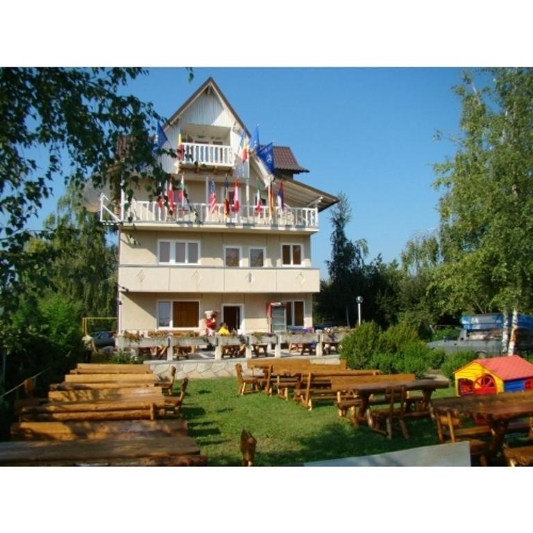 a large white building with wooden tables and benches at Vila Tom Cris in Câmpina