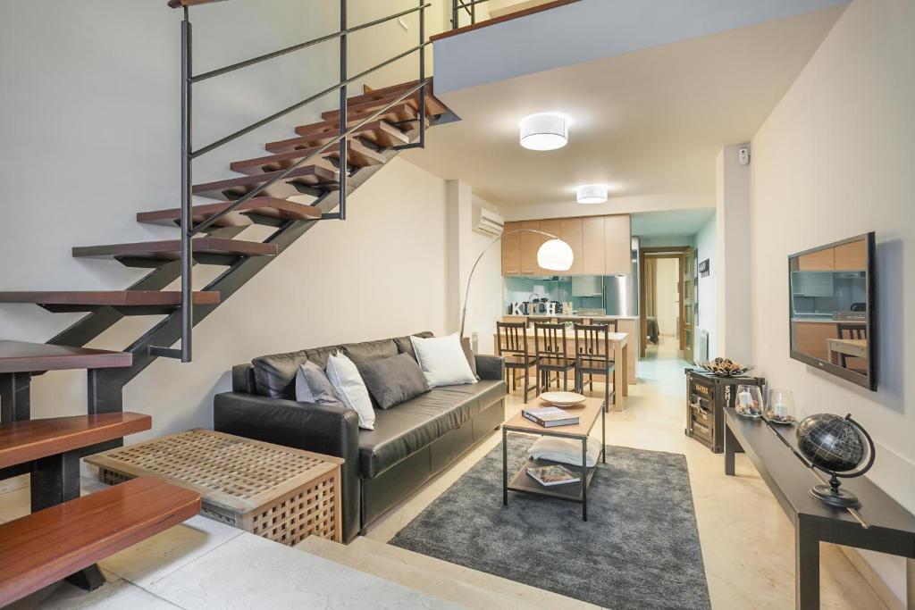 a living room with a couch and a spiral staircase at ApartsNouBcn Fira Barcelona in Hospitalet de Llobregat