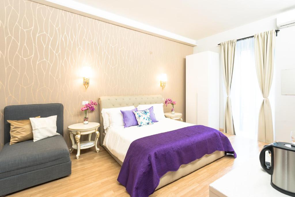 um quarto com uma cama roxa e uma cadeira em BQ House Milizie Luxury Rooms em Roma