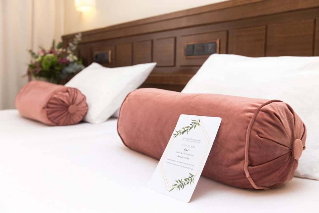 a bed with two pillows and a purse on it at Hotel Garelos Betanzos in Betanzos