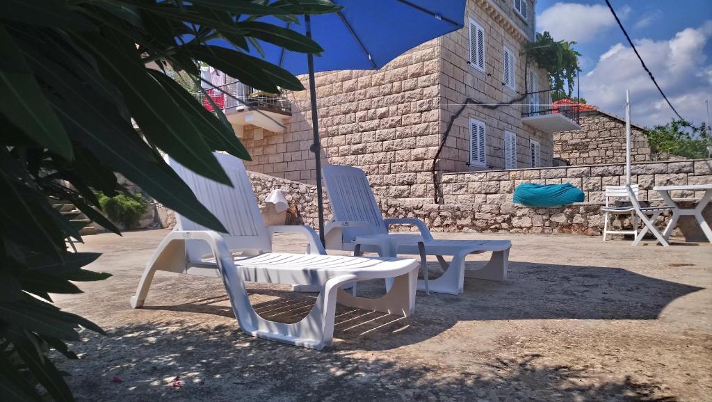 a couple of chairs and a table and an umbrella at Studio Silvana & Room Renata in Lumbarda