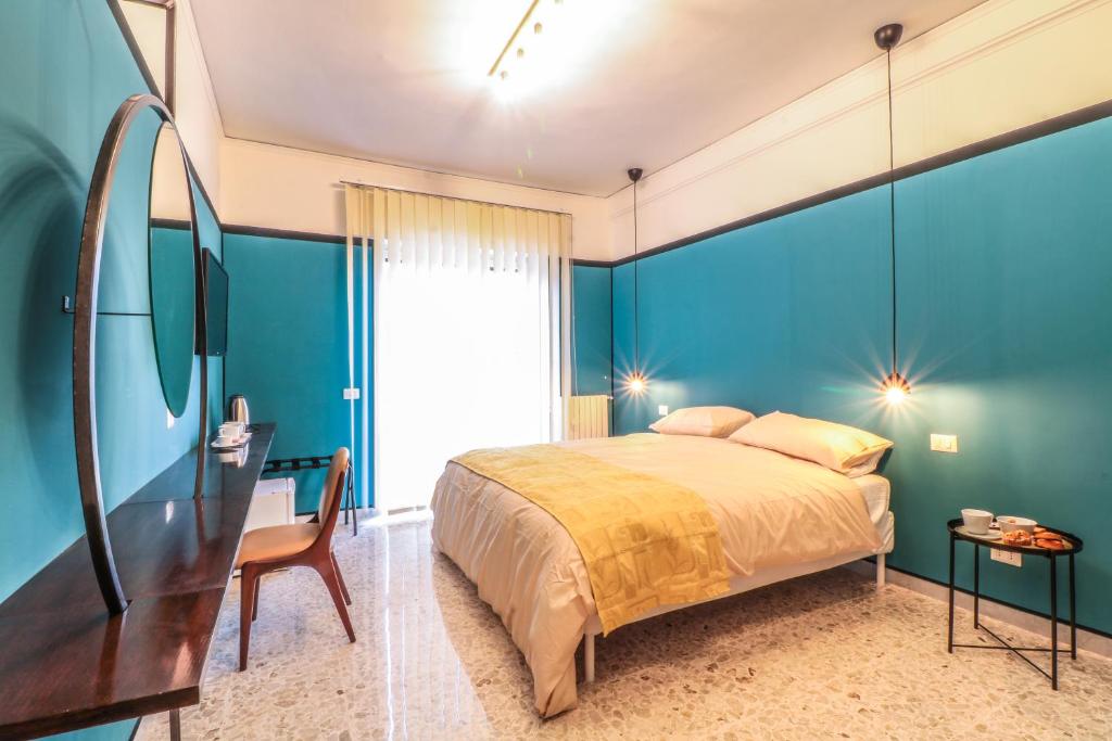 una camera da letto con pareti blu, un letto e una scrivania di Le stanze di Virgilio a Napoli