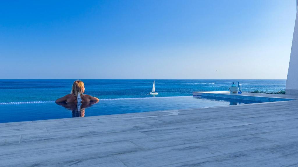 a woman standing next to a swimming pool overlooking the ocean at Villa Lola in Punta Prima