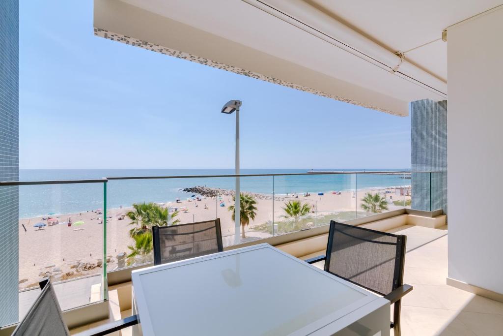 un tavolo con sedie in una camera con vista sulla spiaggia di Brisa do Mar 2Br - Sea front - Luxury apartment a Quarteira