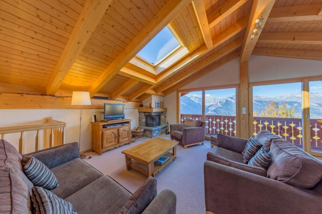 a living room with couches and a television and mountains at Chalet Freya in Nendaz