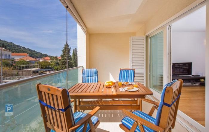 a balcony with a wooden table and chairs on a patio at Dubrovnik Luxury Apartment Lapad in Dubrovnik