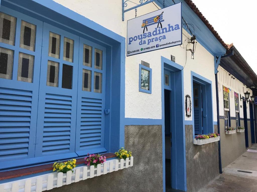 un bâtiment bleu et blanc avec un panneau sur lequel figure un panneau dans l'établissement Pousadinha da Praça, à Conservatória