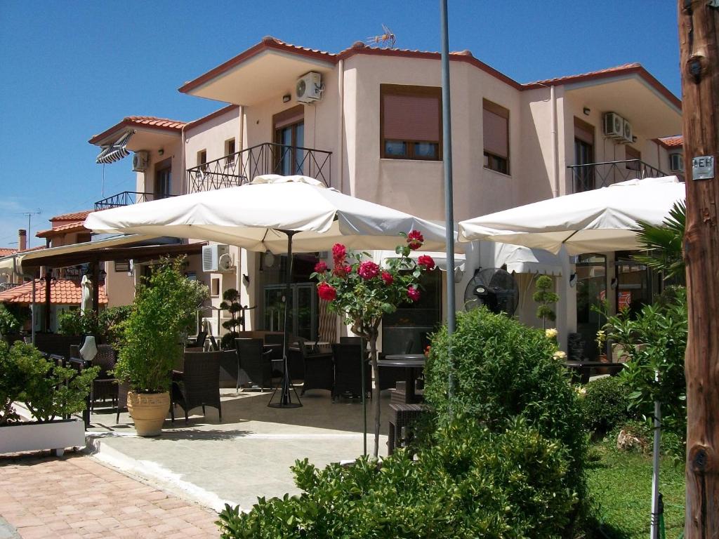 a patio with tables and umbrellas in front of a building at Paschalia ser view studios in Gerakini