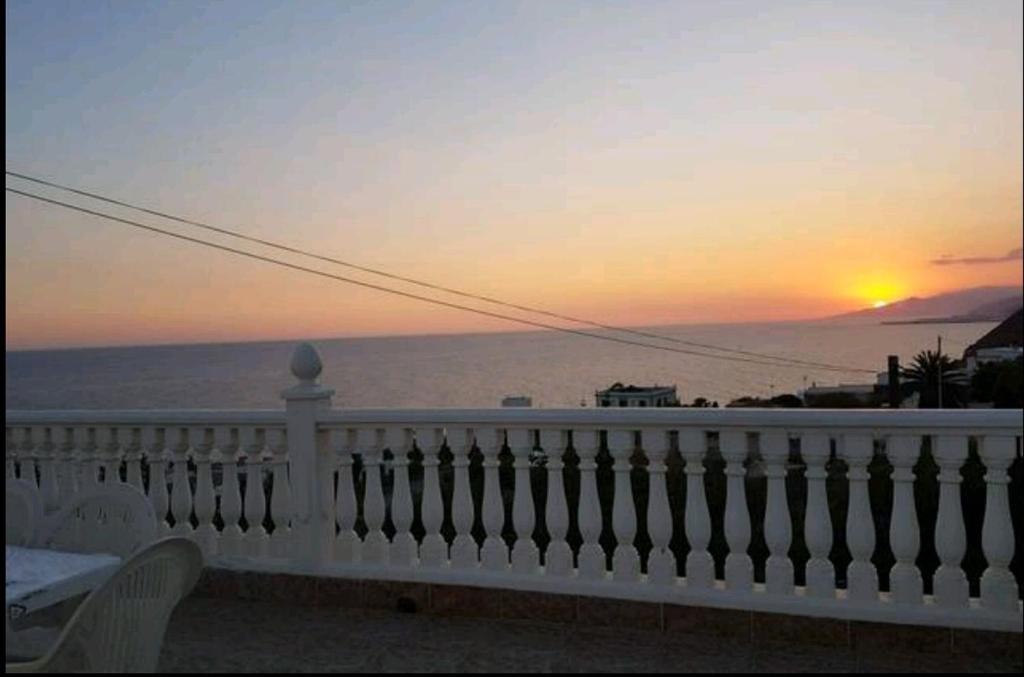 アドラにあるVistas al Marの白い手すり付きのバルコニーから夕日