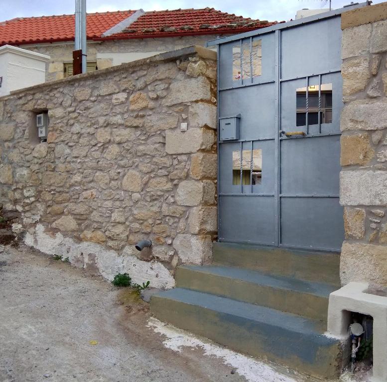- un bâtiment en pierre avec une porte bleue et des escaliers dans l'établissement Petra Guest House, à Áyiai Paraskiaí