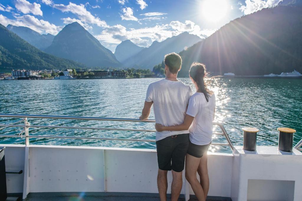 a man and a woman standing on a boat in the water at Fewo an der Seepromenade in Pertisau