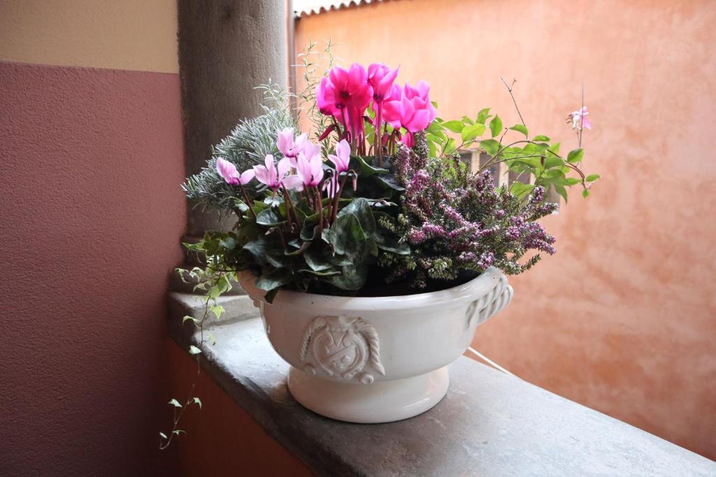 białą wazę wypełnioną kwiatami na parapecie. w obiekcie Papavero 69 w Bergamo