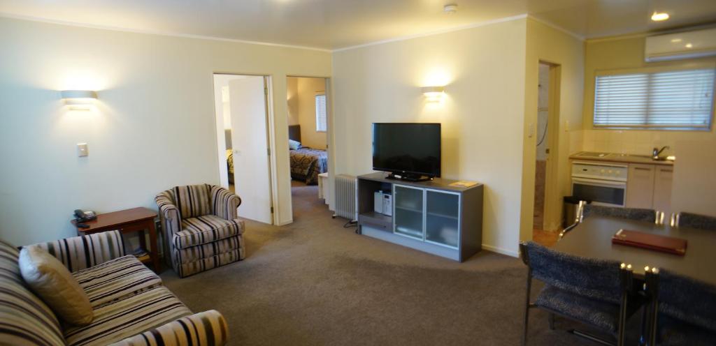 uma sala de estar com um sofá e uma televisão em Cornwall Park Motor Inn em Auckland
