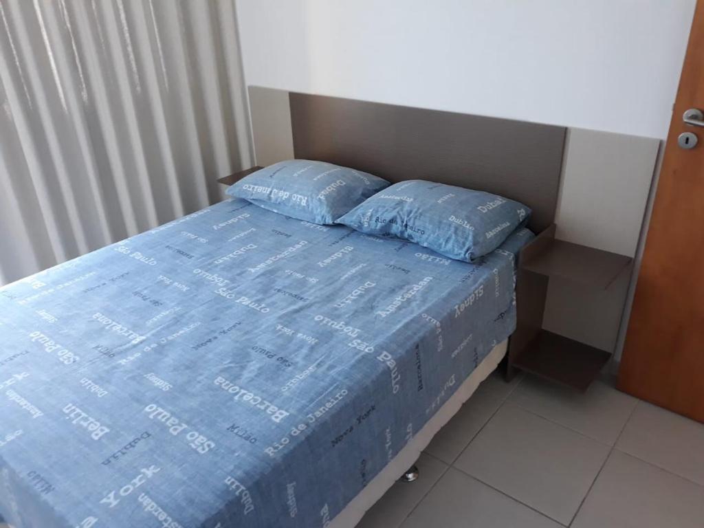 a bed with two blue pillows on top of it at Flat Beira Mar in Recife