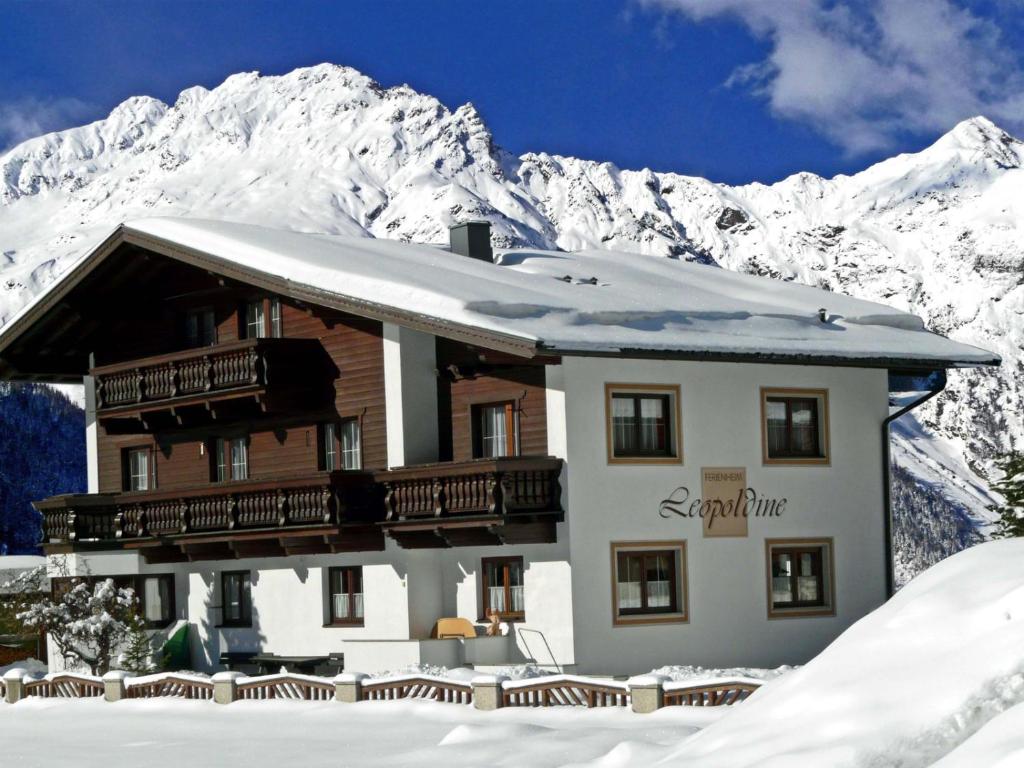 un edificio con montañas cubiertas de nieve en el fondo en Ferienheim Leopoldine, en Längenfeld