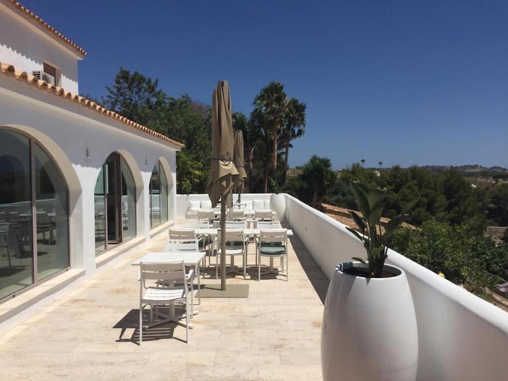 un patio con mesas, sillas y una sombrilla en Abeniss Boutique B&B en Benissa