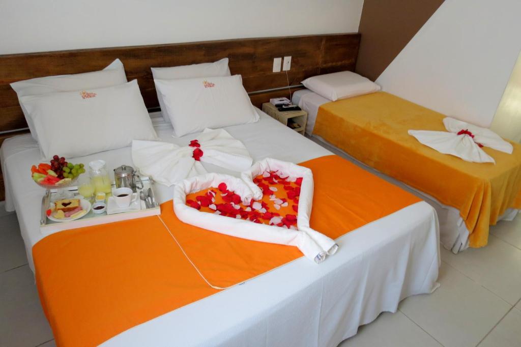 2 Betten in einem Hotelzimmer mit Blumen darauf in der Unterkunft Hotel Encantos de Penedo Alagoas in Penedo