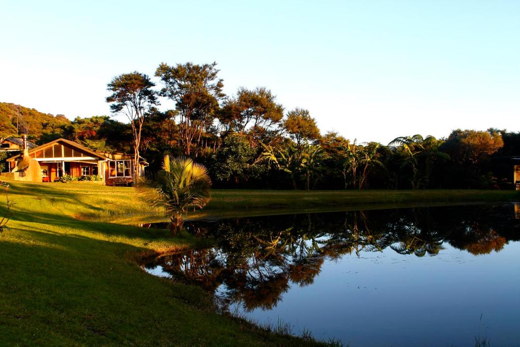 a house sitting next to a lake with a house at Heartland Eco Retreat in Ahipara