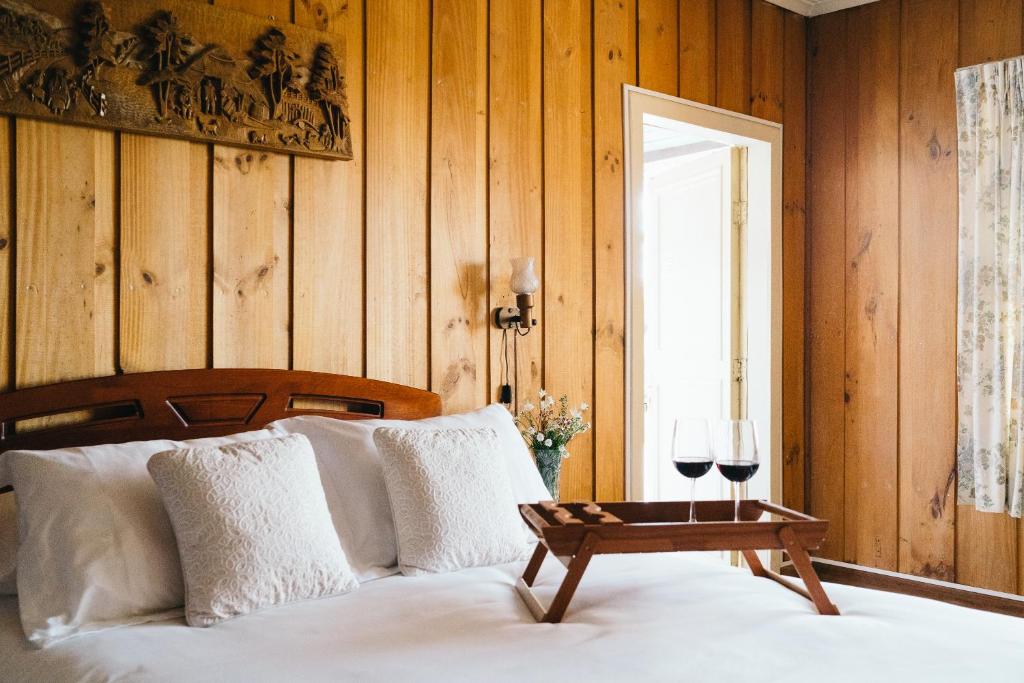 a bedroom with a bed and a table with wine glasses at Hosteria de la Colina in Villarrica