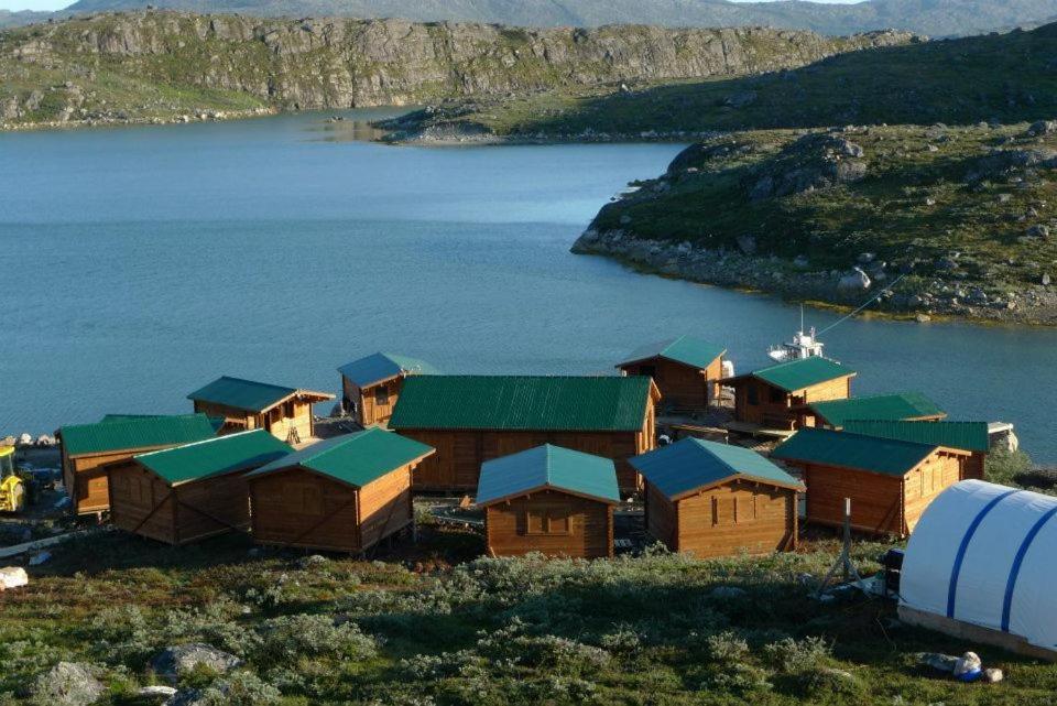 eine Gruppe von Häusern am Rande eines Wasserkörpers in der Unterkunft Lax-á Greenland Camp in Qassimiut