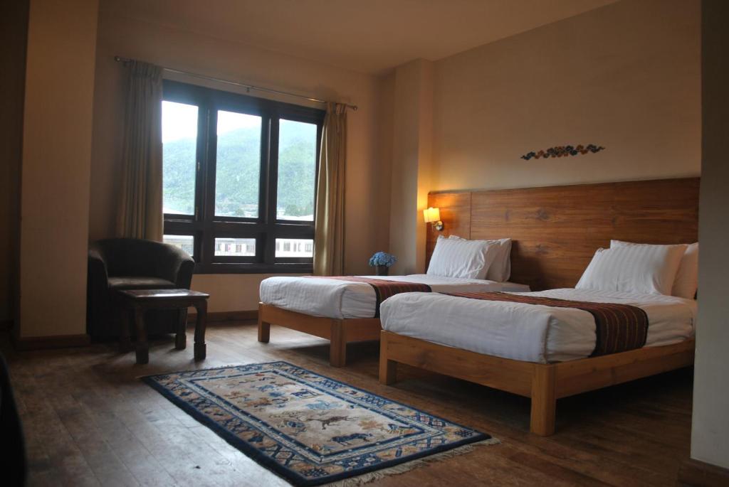 a hotel room with two beds and a window at Gakyil Thimphu in Thimphu