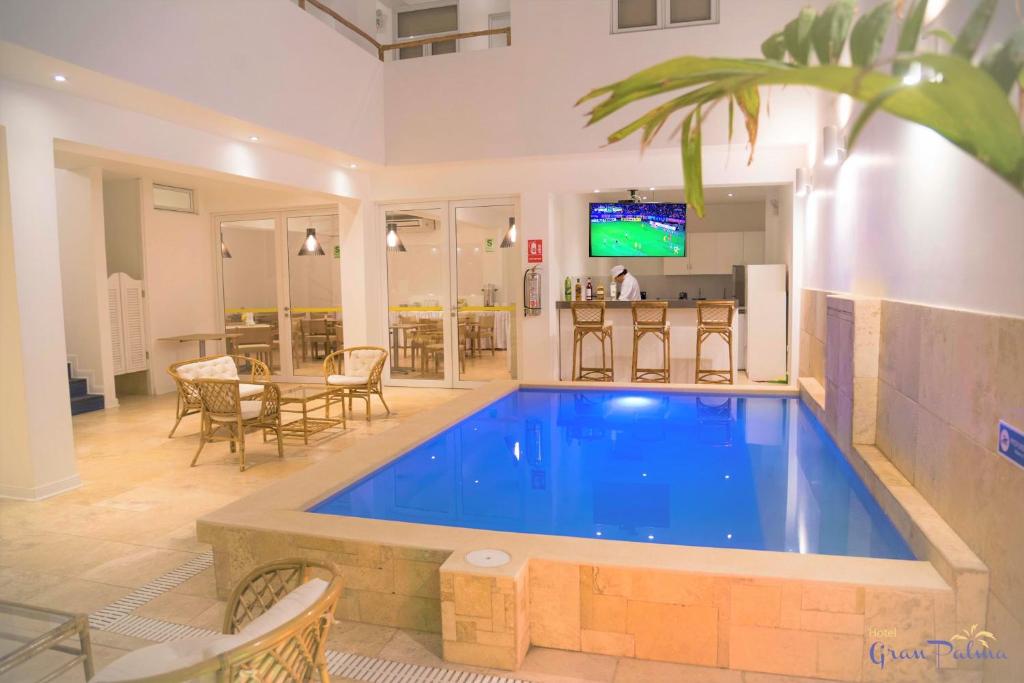 a large swimming pool in a living room with a table at Hotel Gran Palma Talara in Talara