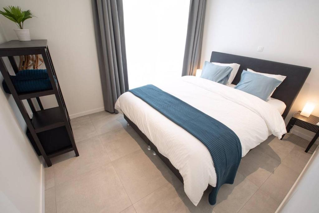 a bedroom with a large bed with white and blue pillows at Studio Brussels - EU-District in Zaventem