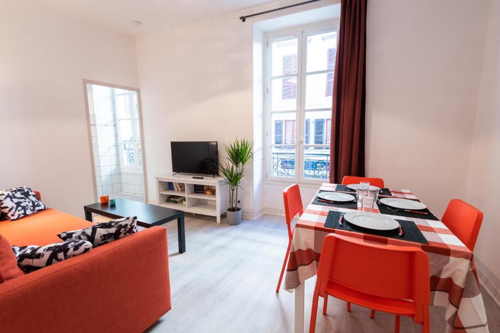 een woonkamer met een tafel en stoelen en een bank bij Appartement cœur de ville - Wifi - Lave-sèche linge in Pau