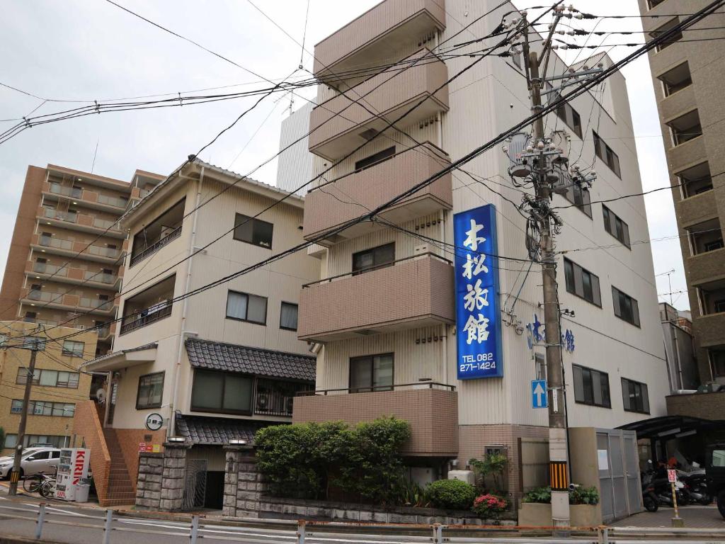 a building with a blue sign in front of it at Kimatsu Ryokan in Hiroshima
