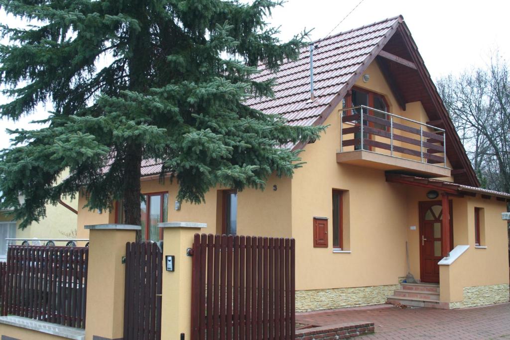 une maison avec une clôture en bois et un arbre dans l'établissement Treasure Deluxe House, à Miskolctapolca