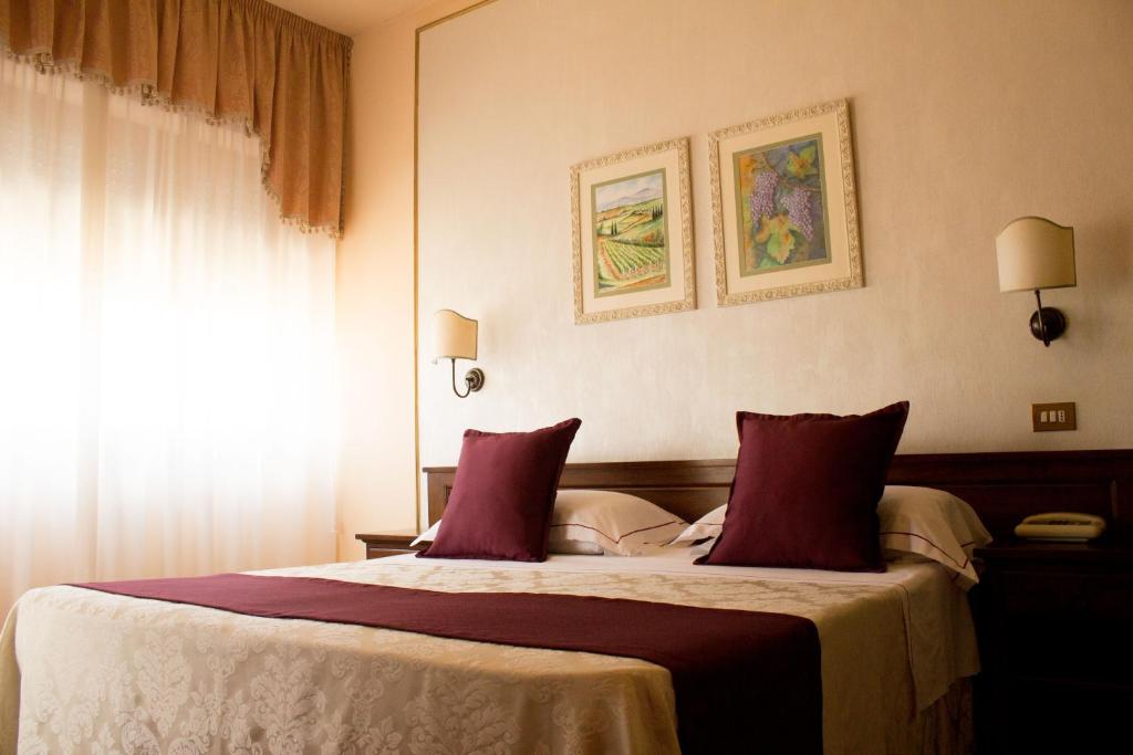 a bedroom with a large bed with red pillows at Hotel Ristorante Tre Stelle in Montepulciano