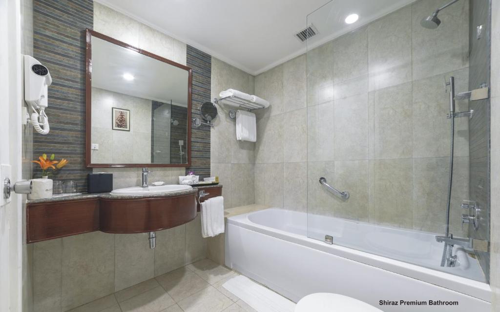 a bathroom with a tub and a sink and a mirror at Hotel Clarks Shiraz in Agra